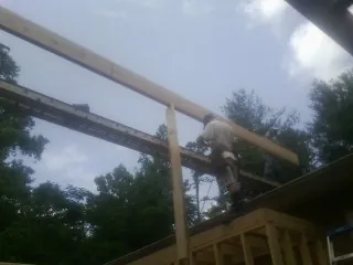 Carpenter setting a ridge beam over a new addition frame — Ice Dam Removal by Roofing Brothers in Mandaree