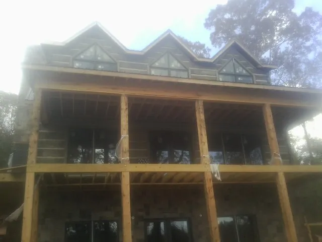 Dormers and porch framing on a large log home under construction — Roof Coating work by our crew in Mandaree
