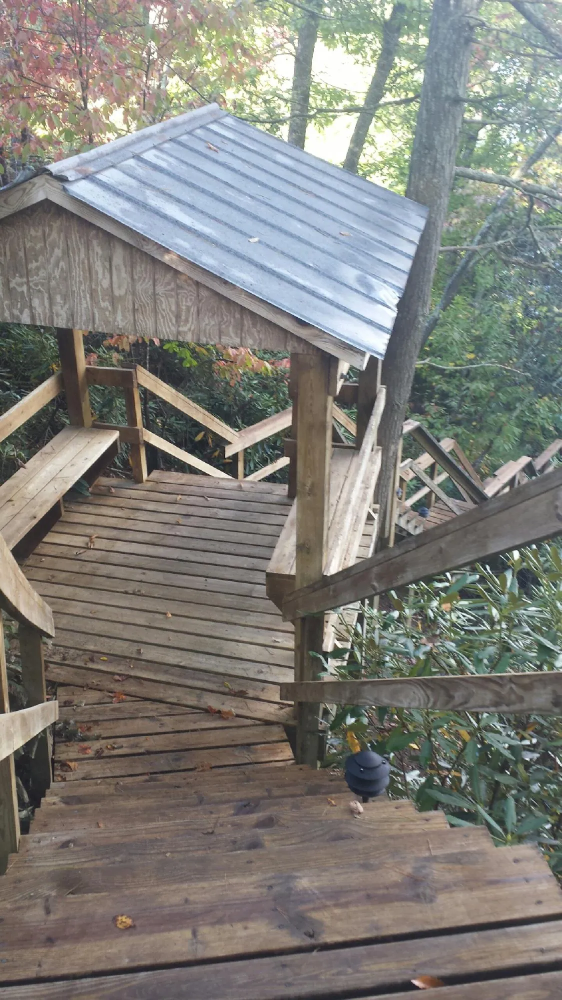 Metal roofed shelter over wooden steps on a wooded walkway — Skylight Repair & Installation work by our crew in Mandaree