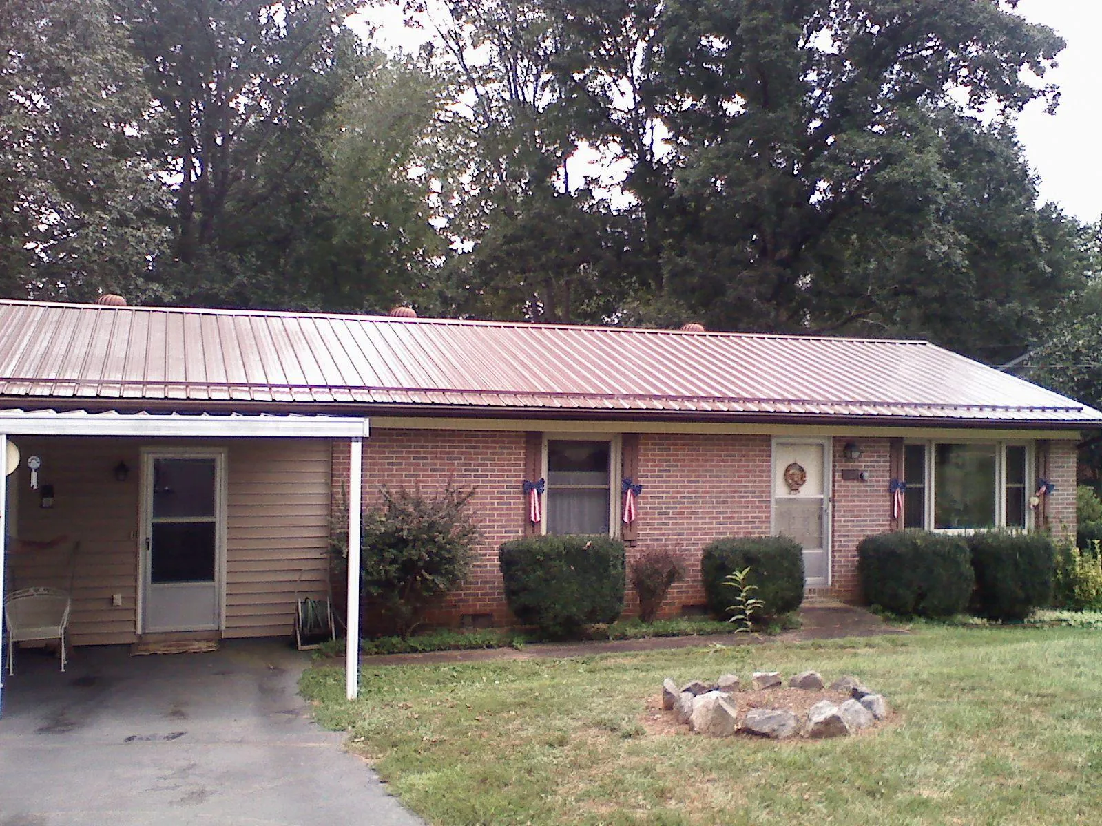 Bronze metal roof and carport on a brick ranch home — Roof Repair work by our crew in Mandaree