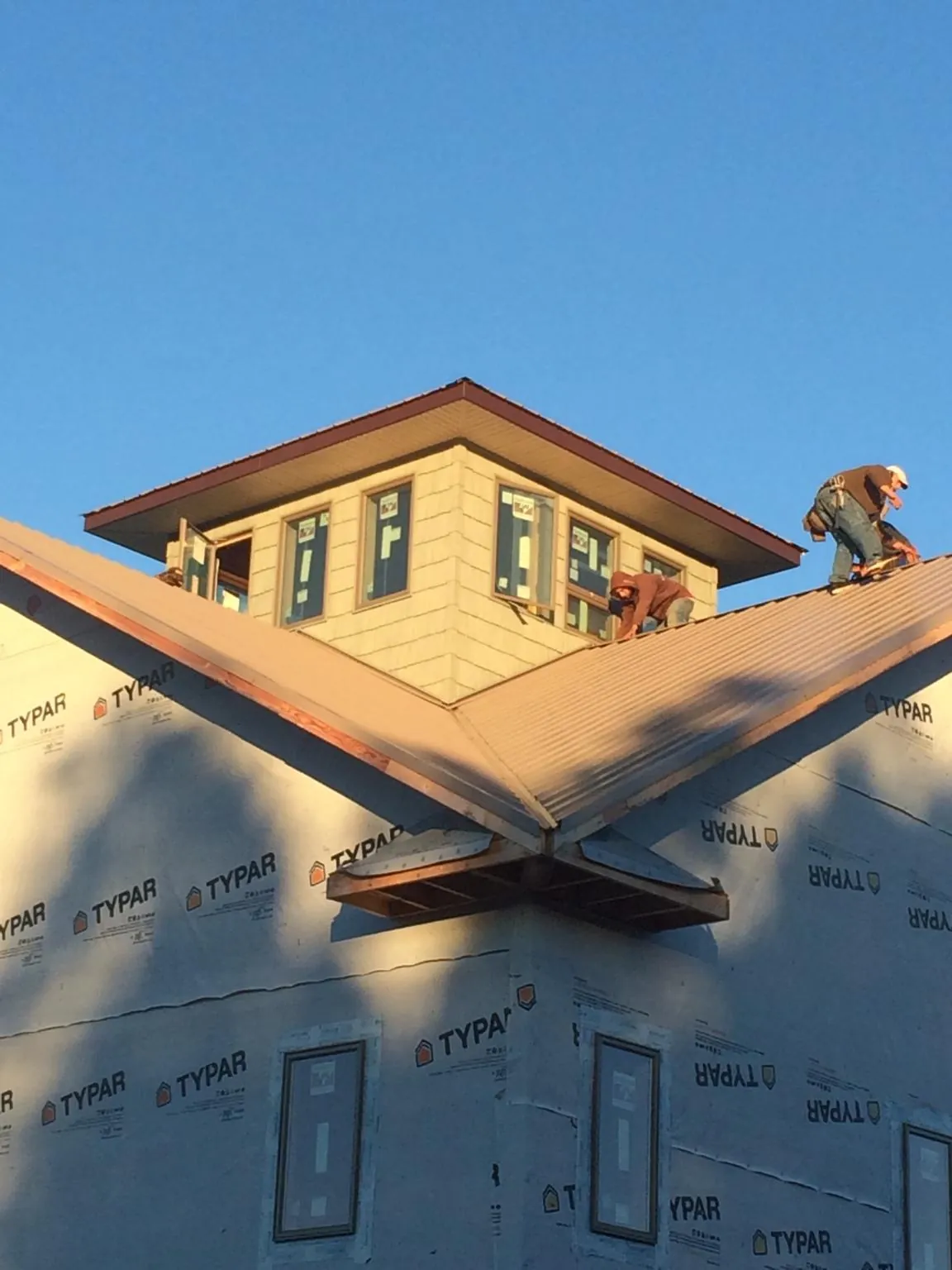 Roofers working around a rooftop cupola on a new metal roof at sunset — Roof Waterproofing in Mandaree by Roofing Brothers